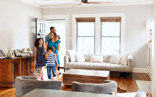 Family of four walking into new home looking happy