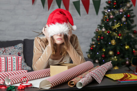 Lady sitting in living room around presents with hat pulled over her eyes