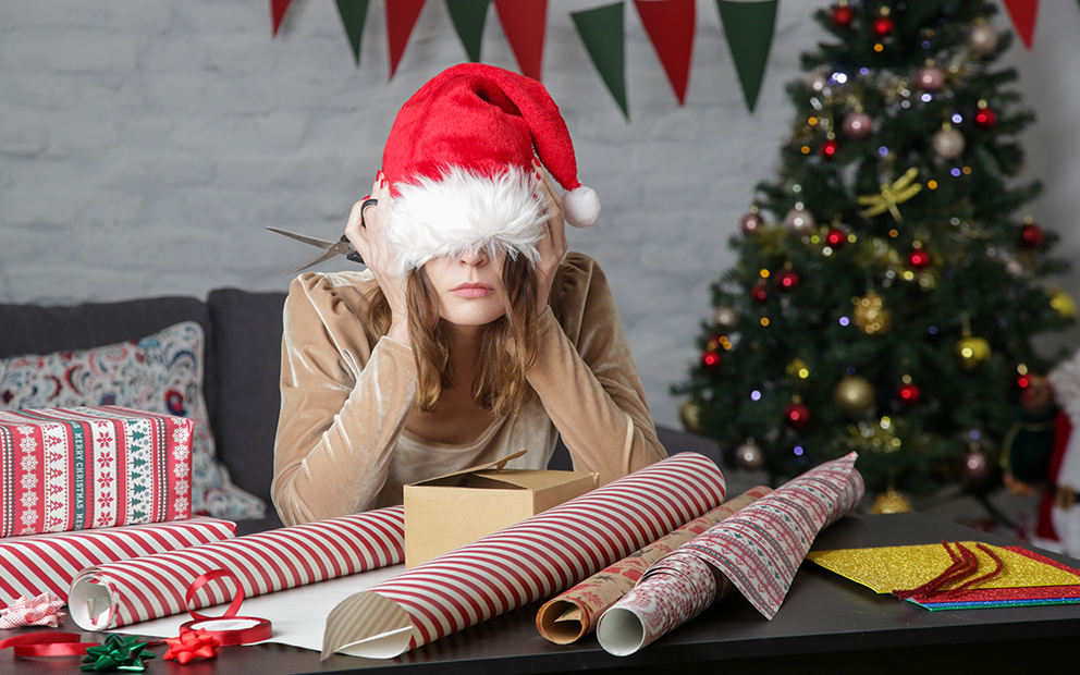 Lady sitting in living room around presents with hat pulled over her eyes