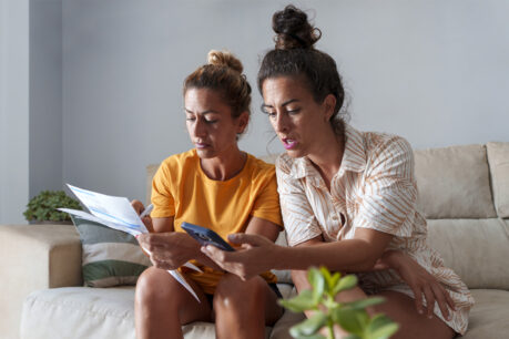 A couple sitting together on couch while they review and discuss documents