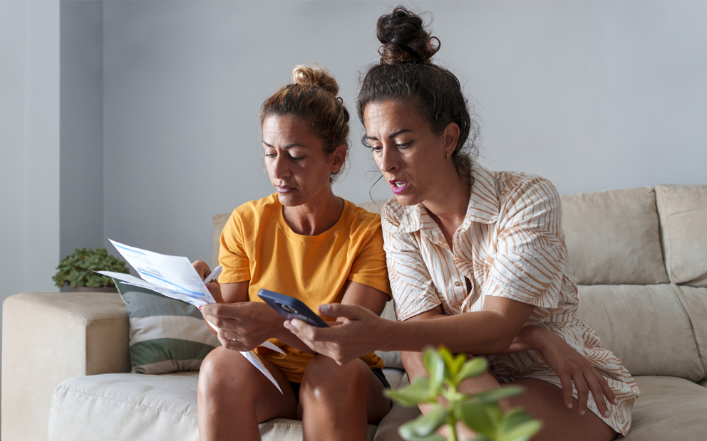 A couple sitting together on couch while they review and discuss documents