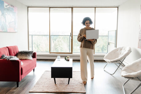 Woman using laptop while walking around in her condo