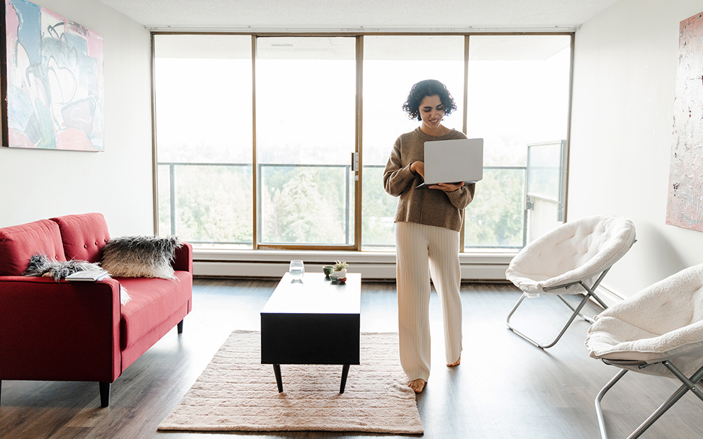 Woman using laptop while walking around in her condo