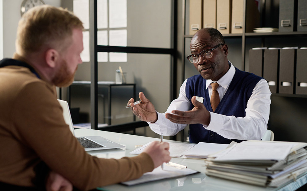 Financial advisor discussing with man as they sit across from each other at a desk