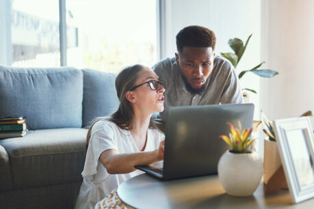 Man and woman looking at documents on laptop together