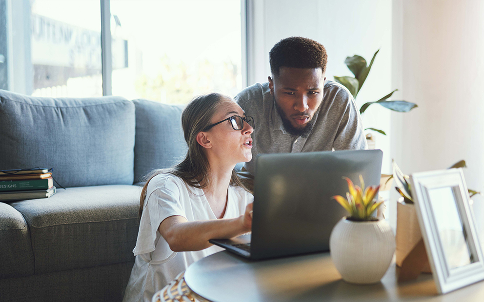 Man and woman looking at documents on laptop together