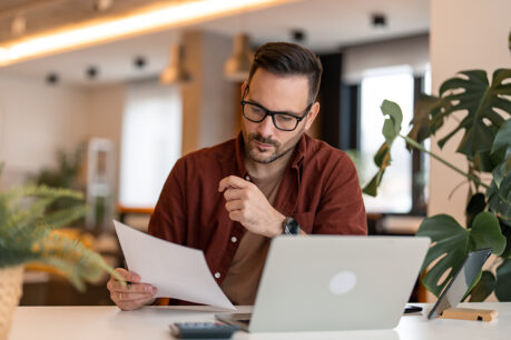 Man sitting at table looking at laptop