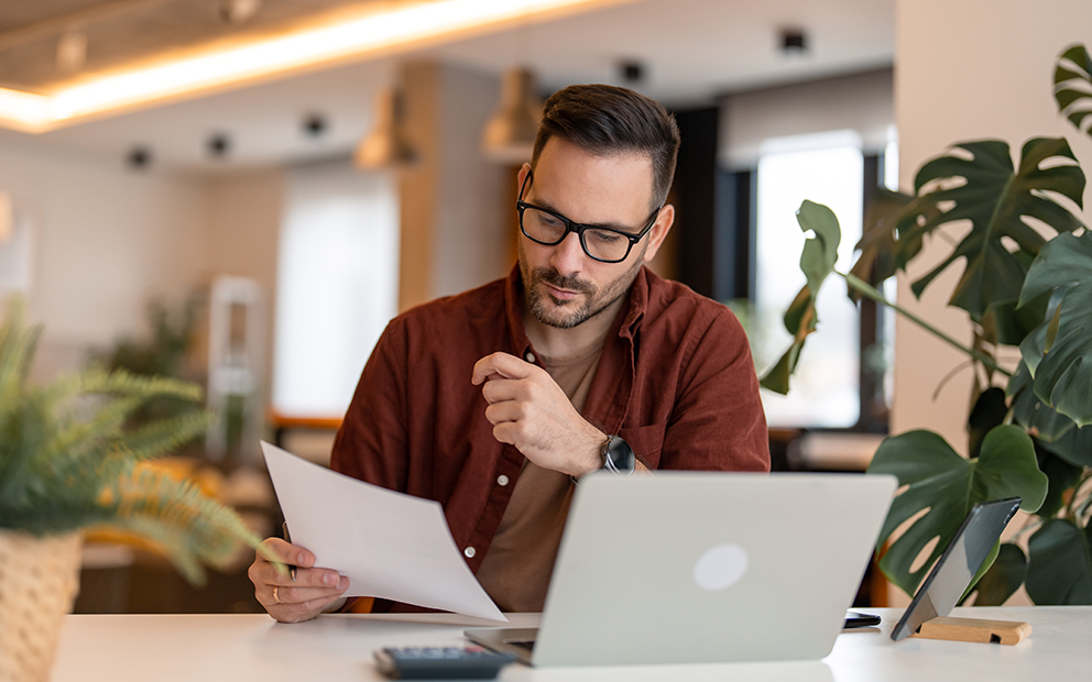 Man sitting at table looking at laptop