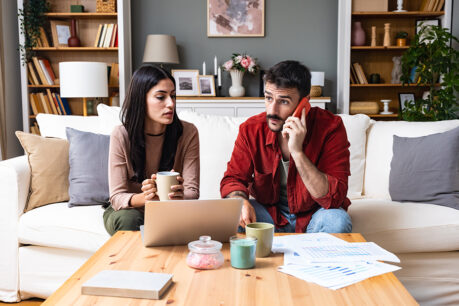 Couple sitting together on couch while reviewing and discussing financial documents