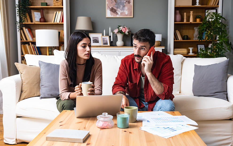 Couple sitting together on couch while reviewing and discussing financial documents